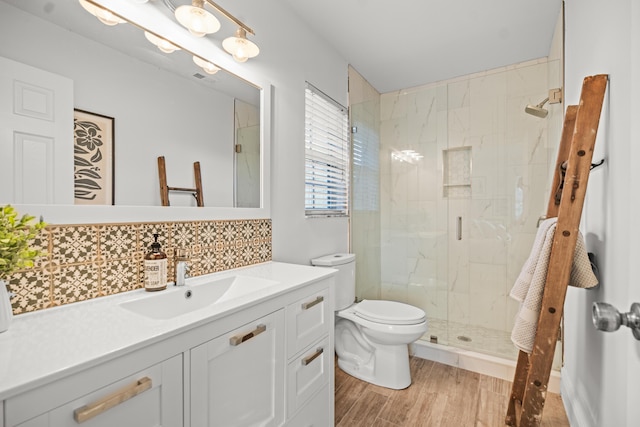 bathroom with backsplash, hardwood / wood-style flooring, vanity, an enclosed shower, and toilet