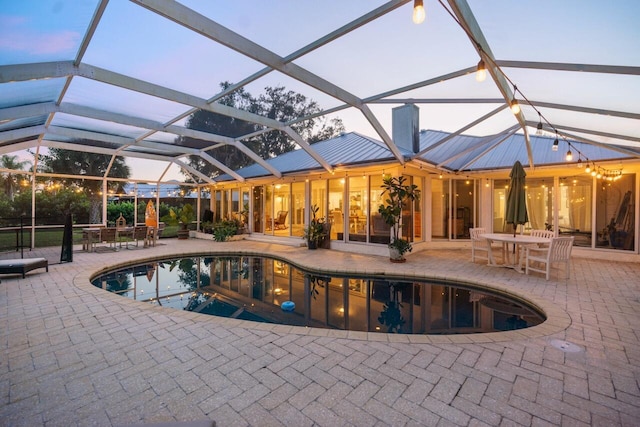 pool at dusk featuring a patio and glass enclosure