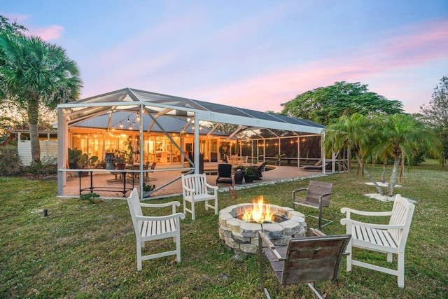 yard at dusk with an outdoor fire pit, a lanai, and a patio