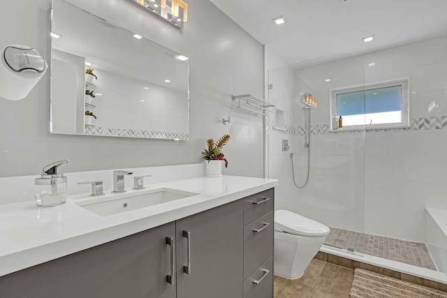 bathroom with vanity, tiled shower, and toilet