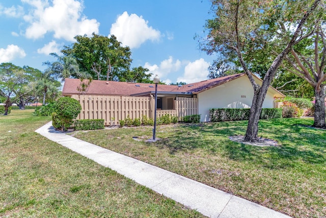 single story home with stucco siding, a front lawn, and fence