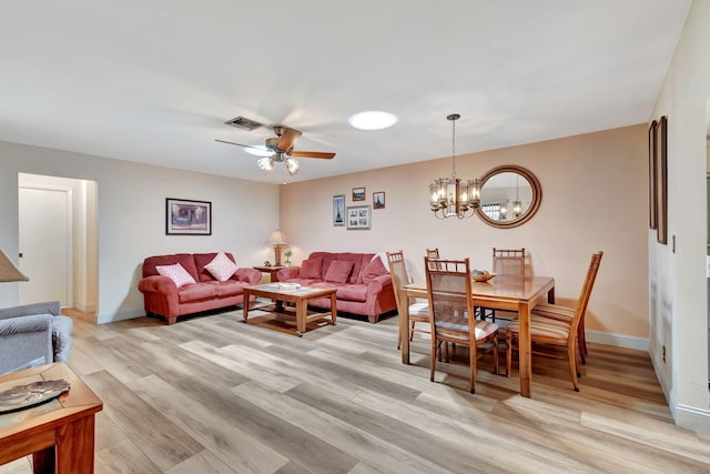 living room with ceiling fan with notable chandelier and light hardwood / wood-style flooring