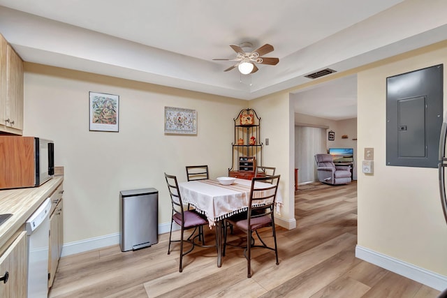 dining area with ceiling fan, electric panel, a raised ceiling, and light hardwood / wood-style flooring