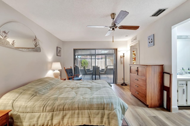 bedroom featuring sink, ceiling fan, access to exterior, a textured ceiling, and light wood-type flooring