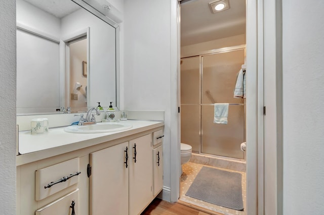 bathroom with vanity, an enclosed shower, hardwood / wood-style floors, and toilet