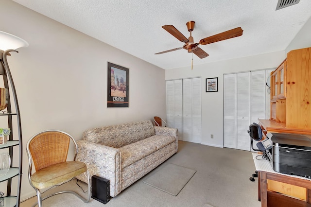 living room featuring carpet, a textured ceiling, and ceiling fan