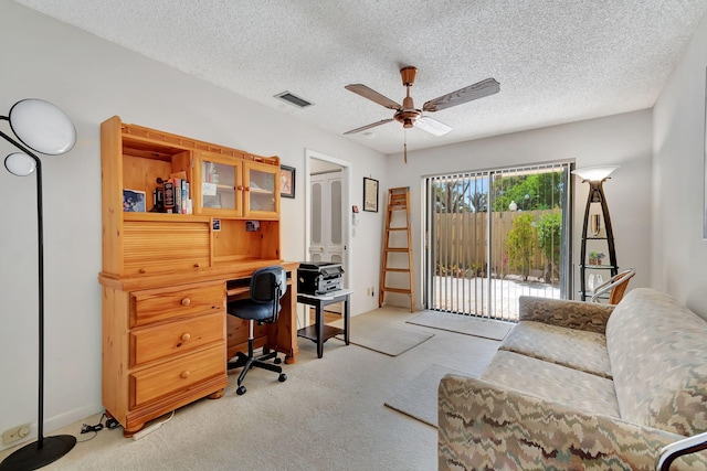 carpeted home office featuring a textured ceiling and ceiling fan