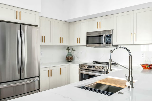 kitchen with white cabinetry, stainless steel appliances, and light stone countertops