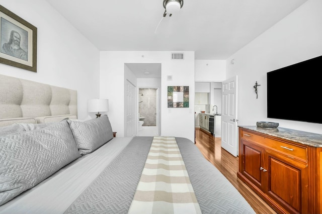 bedroom with connected bathroom, sink, and light hardwood / wood-style floors