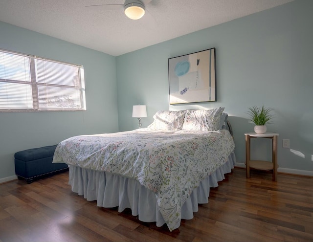 bedroom with ceiling fan, a textured ceiling, and dark hardwood / wood-style flooring