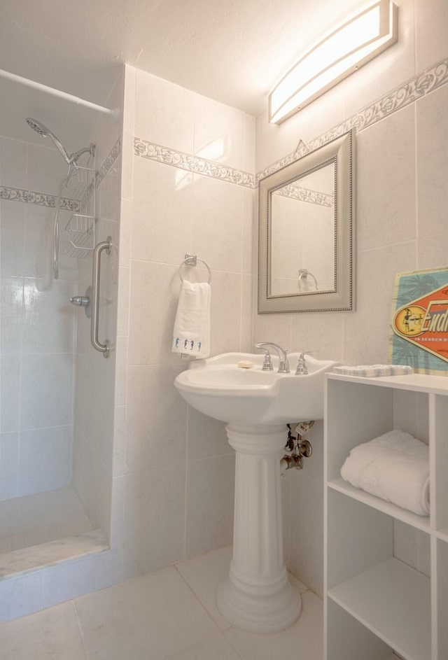 bathroom featuring tiled shower, tile patterned flooring, and tile walls