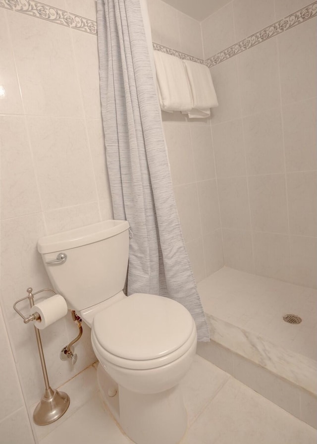 bathroom with toilet, tile walls, tile patterned floors, and walk in shower