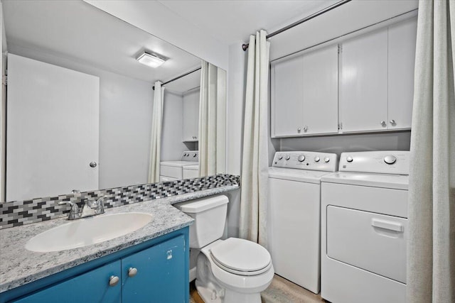 bathroom featuring backsplash, hardwood / wood-style flooring, vanity, washing machine and clothes dryer, and toilet