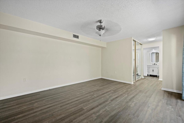 spare room with ceiling fan, dark hardwood / wood-style floors, and a textured ceiling