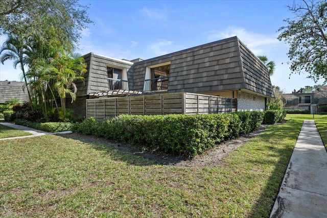 view of side of home with a balcony and a yard