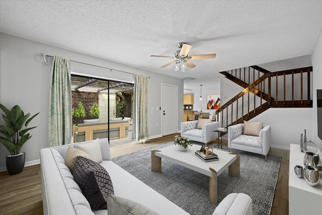 living room with dark wood-type flooring, ceiling fan, and a textured ceiling