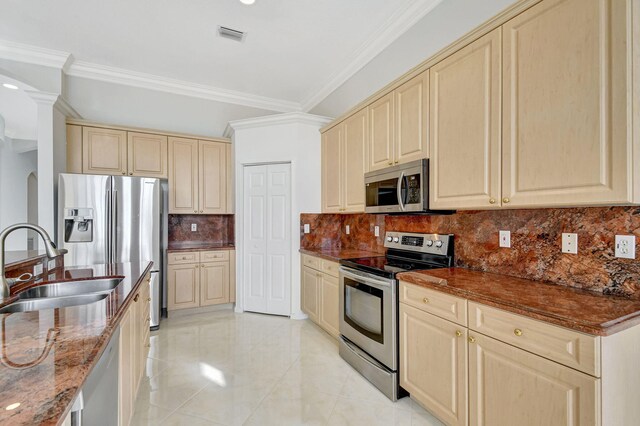 kitchen with light tile patterned flooring, tasteful backsplash, ornamental molding, stainless steel appliances, and cream cabinets