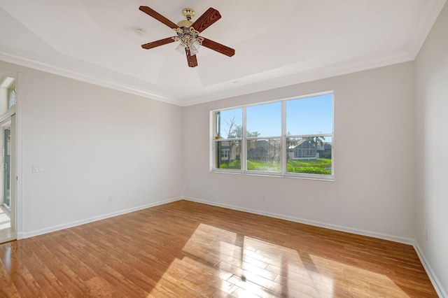 empty room with crown molding, a tray ceiling, and light hardwood / wood-style flooring