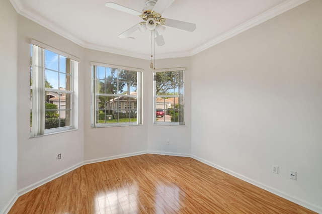 spare room with a ceiling fan, crown molding, baseboards, and wood finished floors
