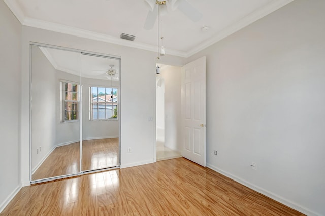 unfurnished bedroom with crown molding, a closet, light wood-style flooring, baseboards, and visible vents