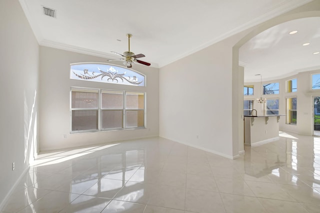 tiled empty room featuring ceiling fan, ornamental molding, and a healthy amount of sunlight