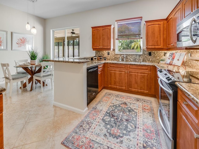 kitchen with light stone countertops, appliances with stainless steel finishes, sink, and pendant lighting