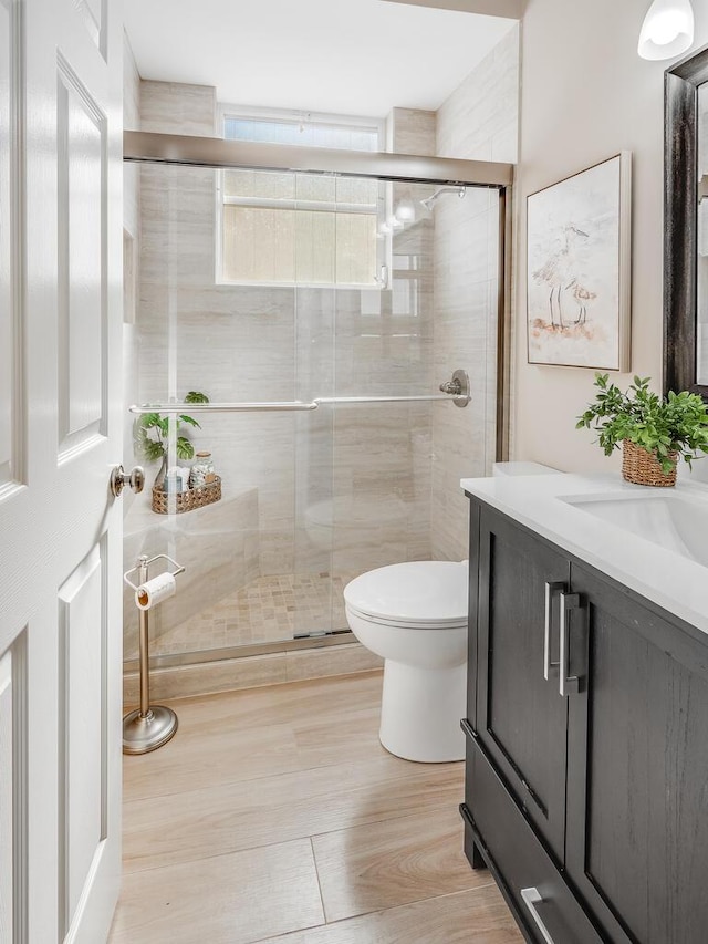 bathroom featuring vanity, a shower with shower door, and toilet