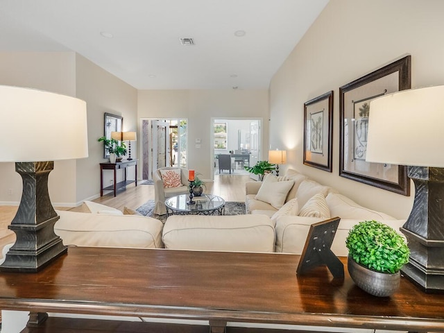 living room featuring lofted ceiling and light hardwood / wood-style floors