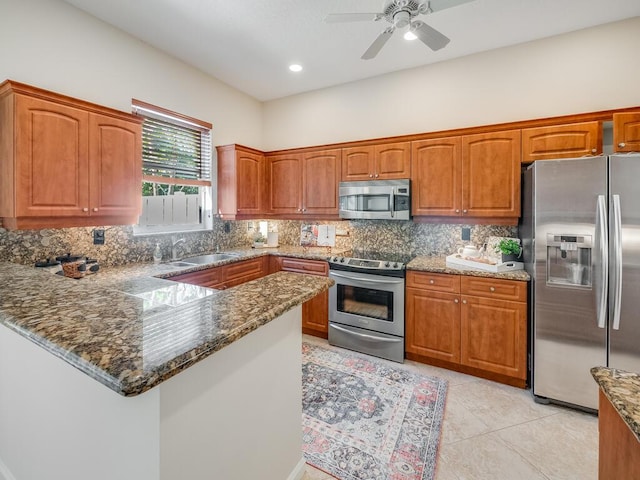 kitchen featuring sink, tasteful backsplash, dark stone countertops, kitchen peninsula, and stainless steel appliances