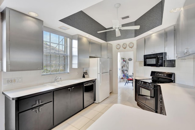 kitchen with sink, light tile patterned floors, gray cabinets, decorative backsplash, and black appliances