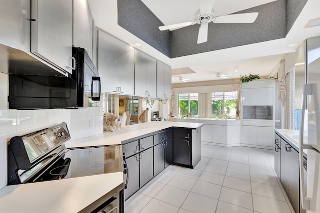 kitchen with light tile patterned floors, ceiling fan, decorative backsplash, stainless steel range with electric cooktop, and kitchen peninsula