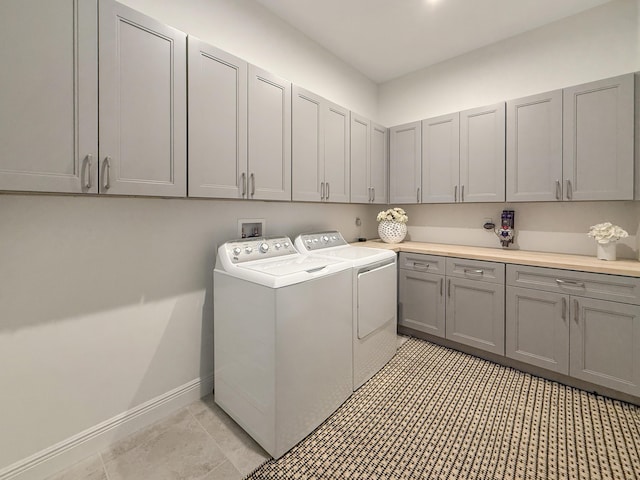 clothes washing area with cabinets, separate washer and dryer, and light tile patterned floors