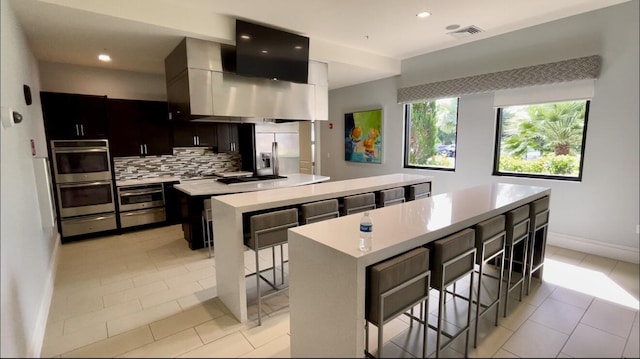 kitchen featuring decorative backsplash, stainless steel appliances, a center island, and a breakfast bar