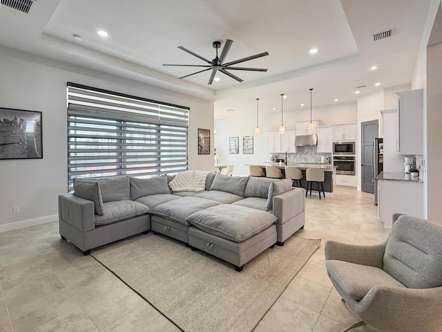 tiled living room featuring a tray ceiling and ceiling fan