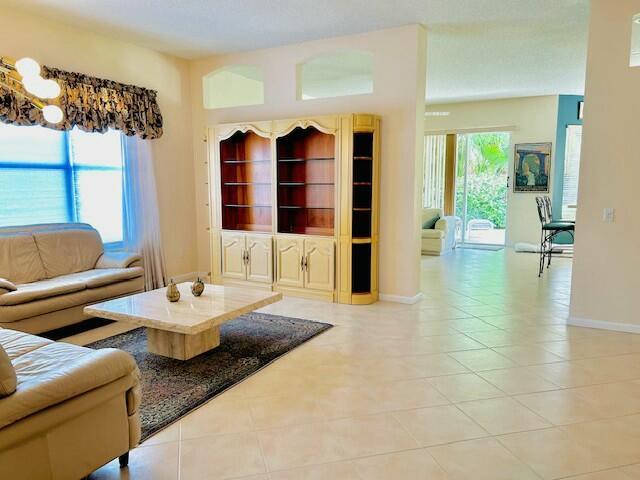 living room featuring light tile patterned floors, built in shelves, and a healthy amount of sunlight