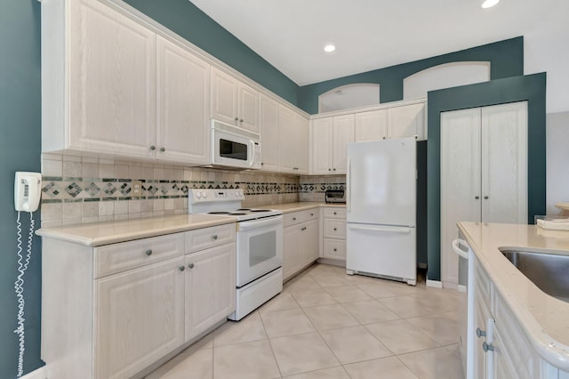 kitchen featuring light tile patterned floors, white appliances, decorative backsplash, and white cabinets