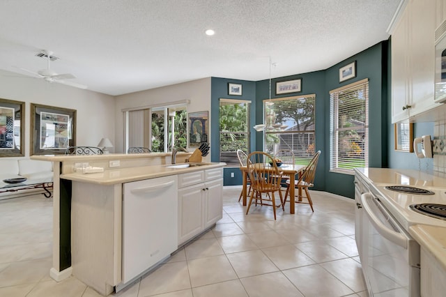 kitchen with sink, a textured ceiling, a center island with sink, white appliances, and white cabinets