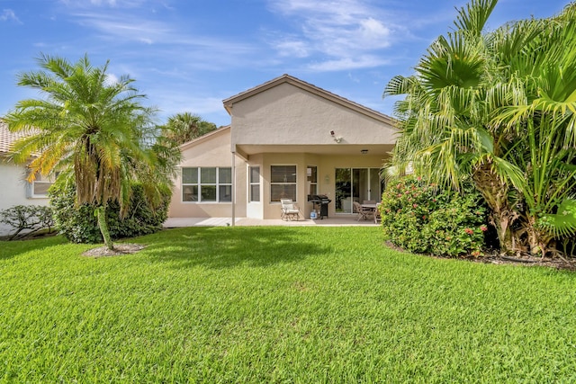 rear view of property with a yard and a patio