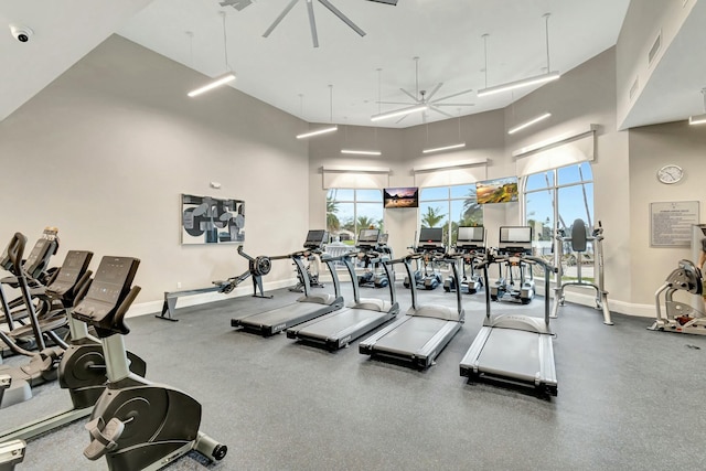 exercise room with ceiling fan and a towering ceiling