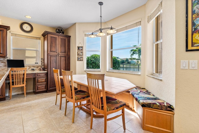 dining space with light tile patterned flooring, built in desk, and a textured ceiling