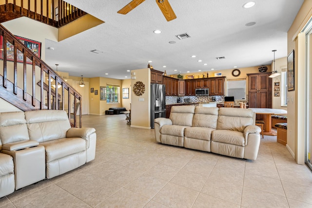 tiled living room featuring ceiling fan and a textured ceiling