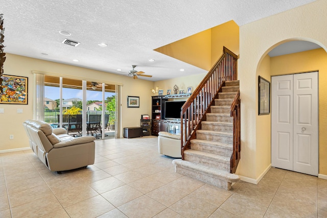 living room with ceiling fan, light tile patterned floors, and a textured ceiling