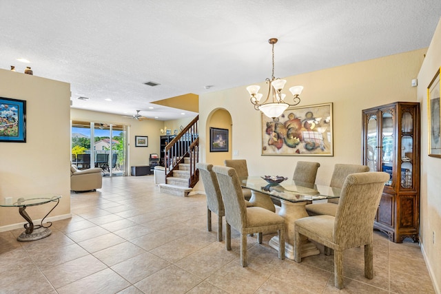 dining room with ceiling fan with notable chandelier, light tile patterned floors, and a textured ceiling