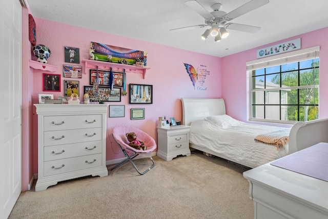 bedroom featuring ceiling fan, light colored carpet, and a textured ceiling