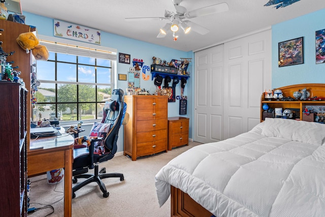 bedroom featuring a textured ceiling, light colored carpet, a closet, and ceiling fan