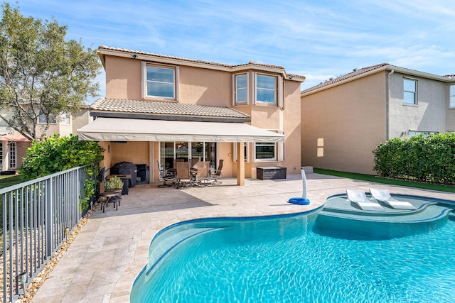 back of property with a fenced in pool and a patio