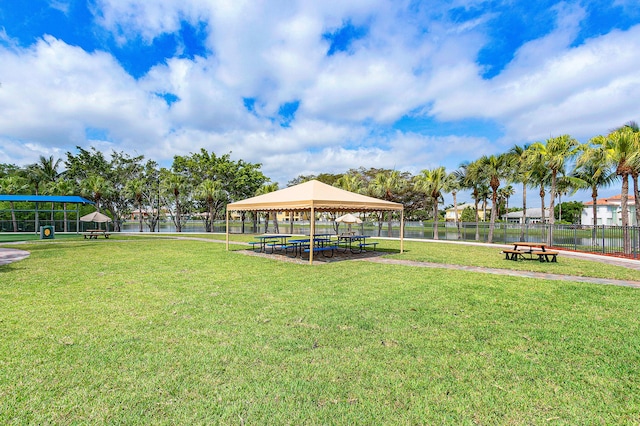 surrounding community with a water view, a gazebo, and a lawn