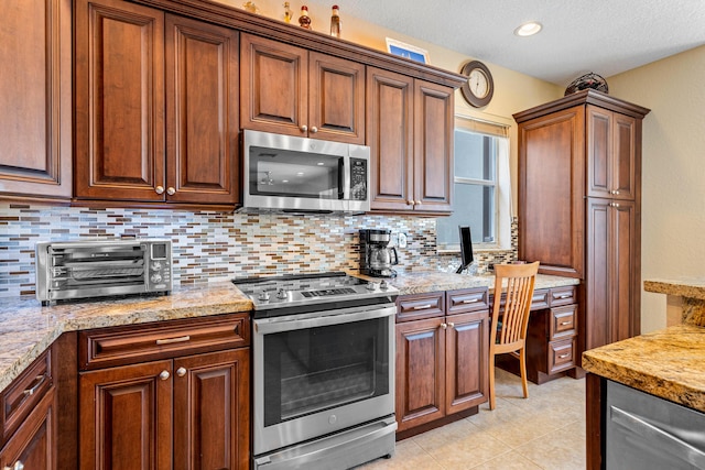 kitchen with light tile patterned flooring, stainless steel appliances, built in desk, and tasteful backsplash