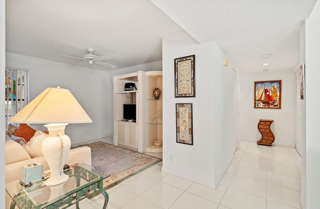 tiled living room with ceiling fan and a textured ceiling