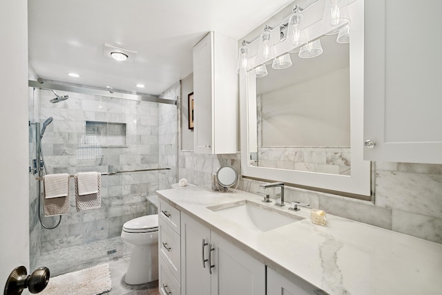 bathroom with vanity, a shower with shower door, tile walls, and toilet